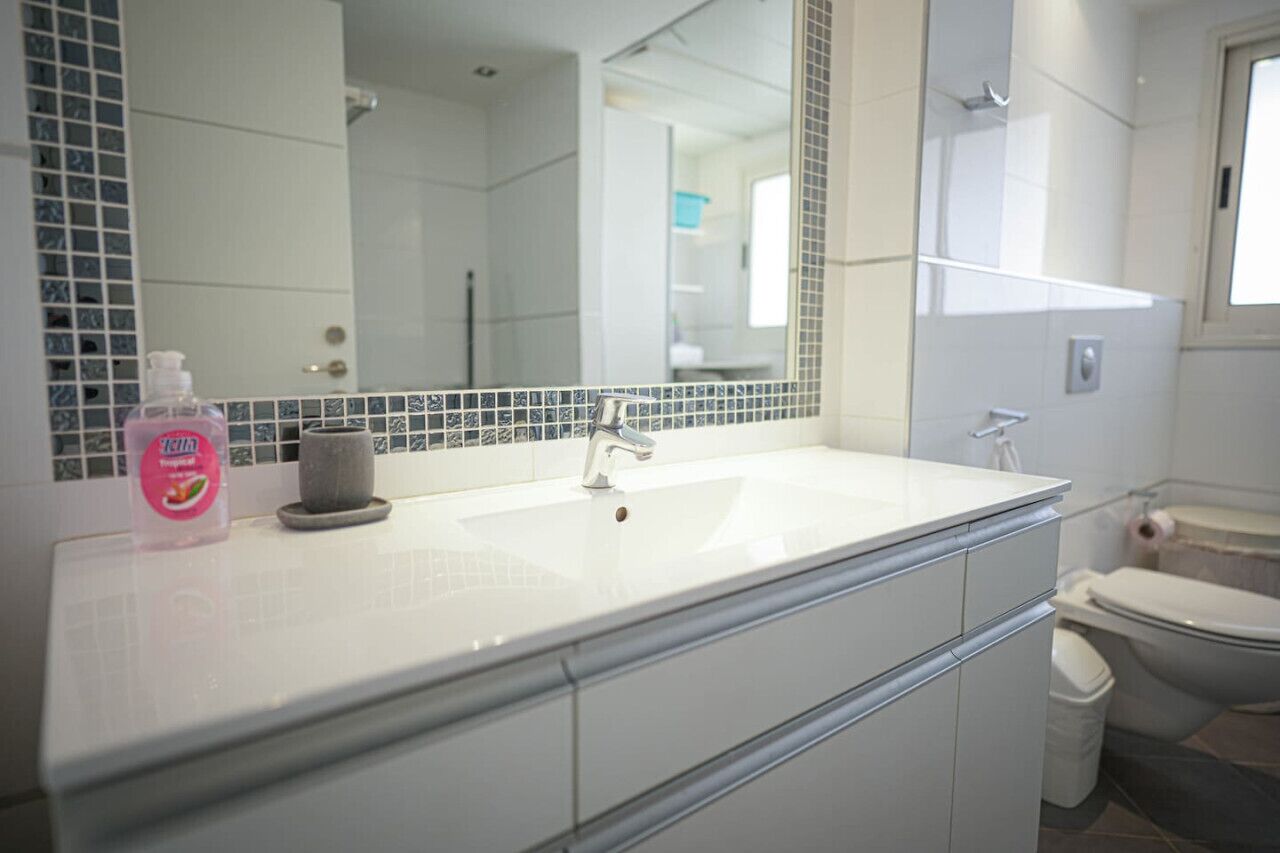 A bathroom with a white sink, a mirror, and a toilet.