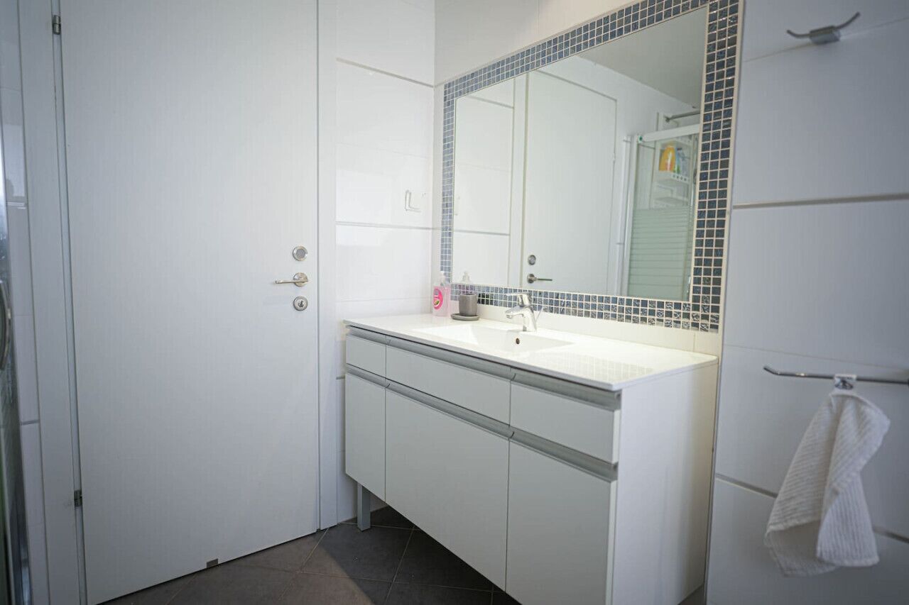 A bathroom with a white sink, a mirror with a blue-tiled frame, and a towel rack.