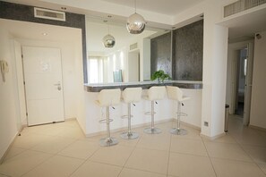 Cozinha moderna com ilha central, banquetas e iluminação pendente.