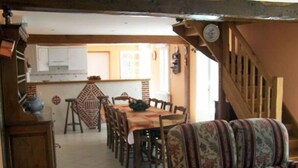 A dining area with a table and chairs, a patterned sofa, and a staircase leading to an upper level. - Country gite with enclosed garden located 1 hour 15 from the seaside (Mesnil-en-Ouche)