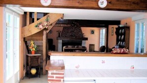 A kitchen with a brick fireplace, wooden beams, and a small staircase leading to another level. - Country gite with enclosed garden located 1 hour 15 from the seaside (Mesnil-en-Ouche)