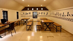 A conference room with long tables, chairs, and a computer on one table. - Ayurguru ayurvedic kalari Resort (Sulthan Bathery)