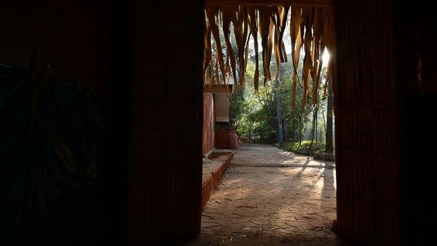 A corridor with a stone floor leading to a wooden door. - Ayurguru ayurvedic kalari Resort (Sulthan Bathery)