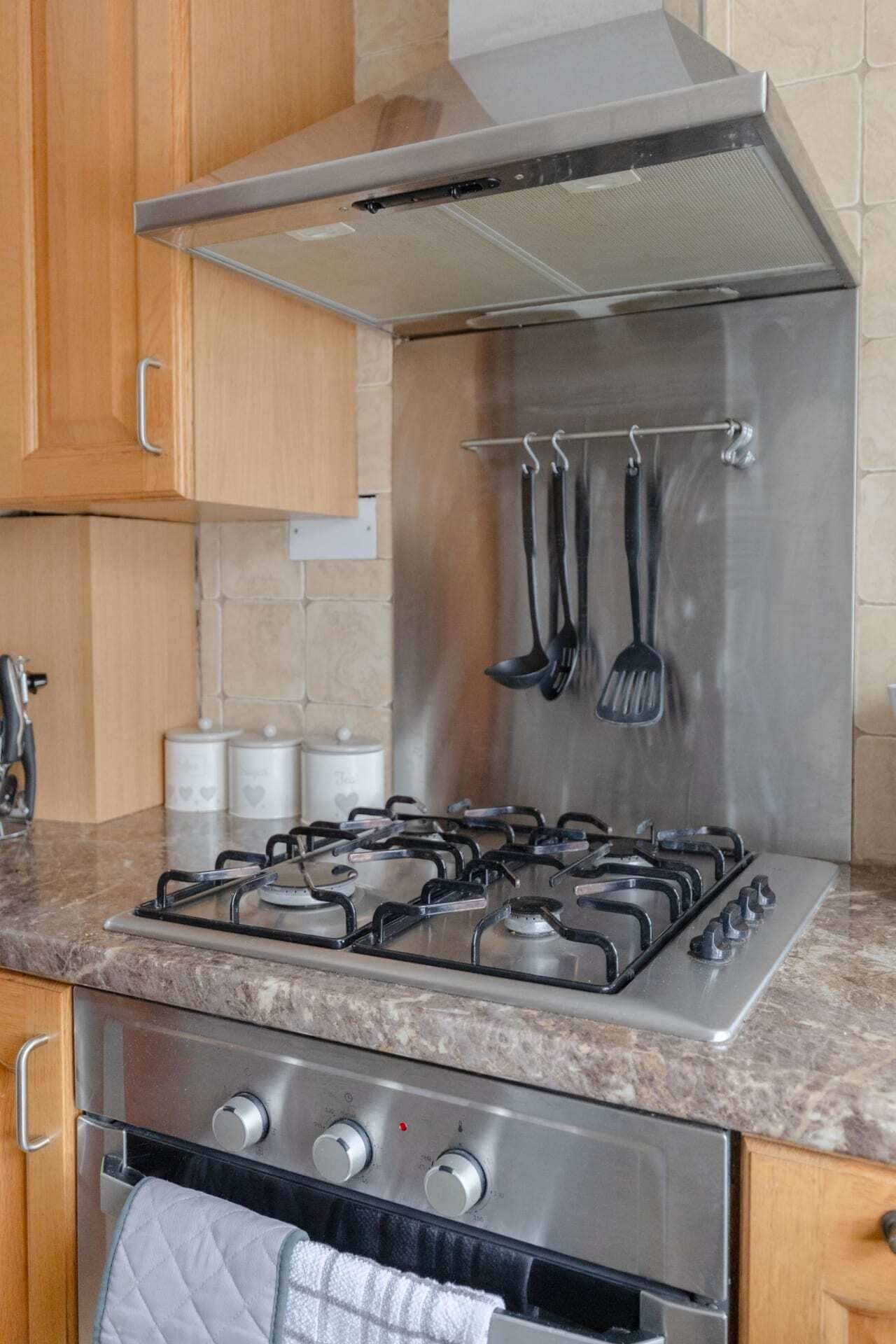 Eine Küche mit einem Edelstahlherd, einem Backofen und einer Dunstabzugshaube.