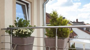 A balcony with two wicker planters, a metal railing, and a view of the sky and neighboring buildings. - FeWo Engler Doppelzimmer Gartenstraße (Lueneburg)