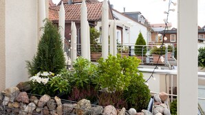 A balcony with potted plants, a railing, and a view of neighboring houses. - FeWo Engler Doppelzimmer Gartenstraße (Lueneburg)