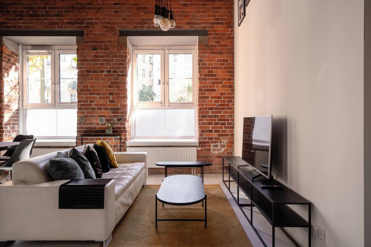A modern living room with a white sofa, a small table, and a TV on a black stand.