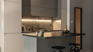 Une cuisine moderne dotée d’un îlot central, de tabourets de bar et d’un four encastré.