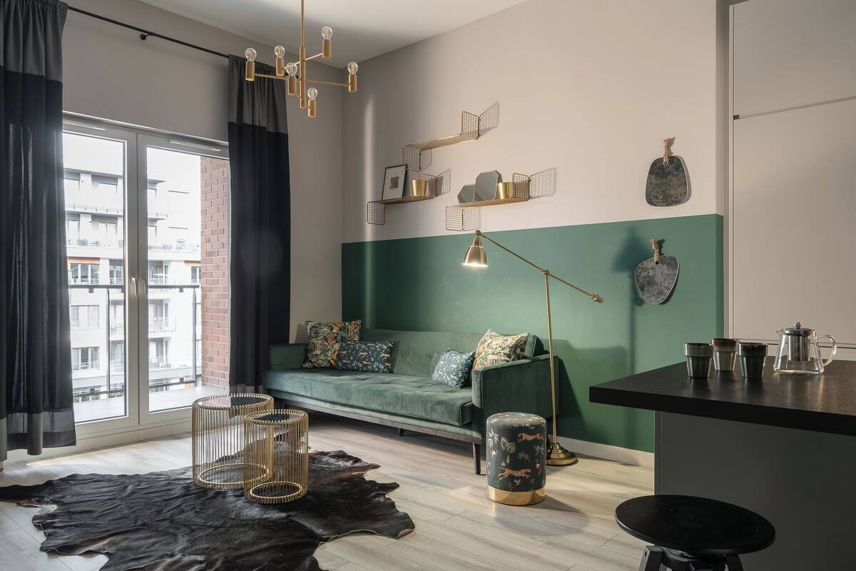 A modern living room with a green sofa, a coffee table, and a dining area with a black countertop.