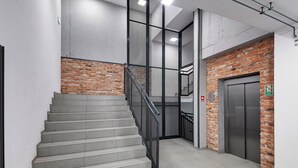 Un escalier avec des rampes en métal, un mur en briques et un ascenseur.