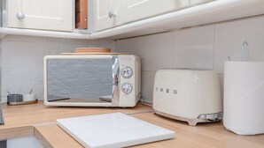 Una cocina con tostadora, microondas y tabla de cortar sobre la encimera.