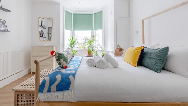 Un dormitorio con cama, ventana, cómoda y espejo.