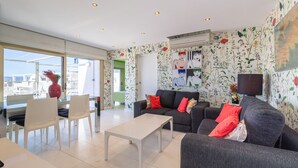 En moderne stue med en grå sofa, et hvidt sofabord og et spisebord i glas med stole.