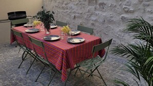 Comedor con una mesa lista para cuatro personas, rodeada de sillas, frente a una pared con textura.