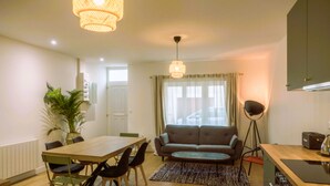 Una sala de estar moderna con una mesa de comedor, sofá y un ventanal con cortinas.
