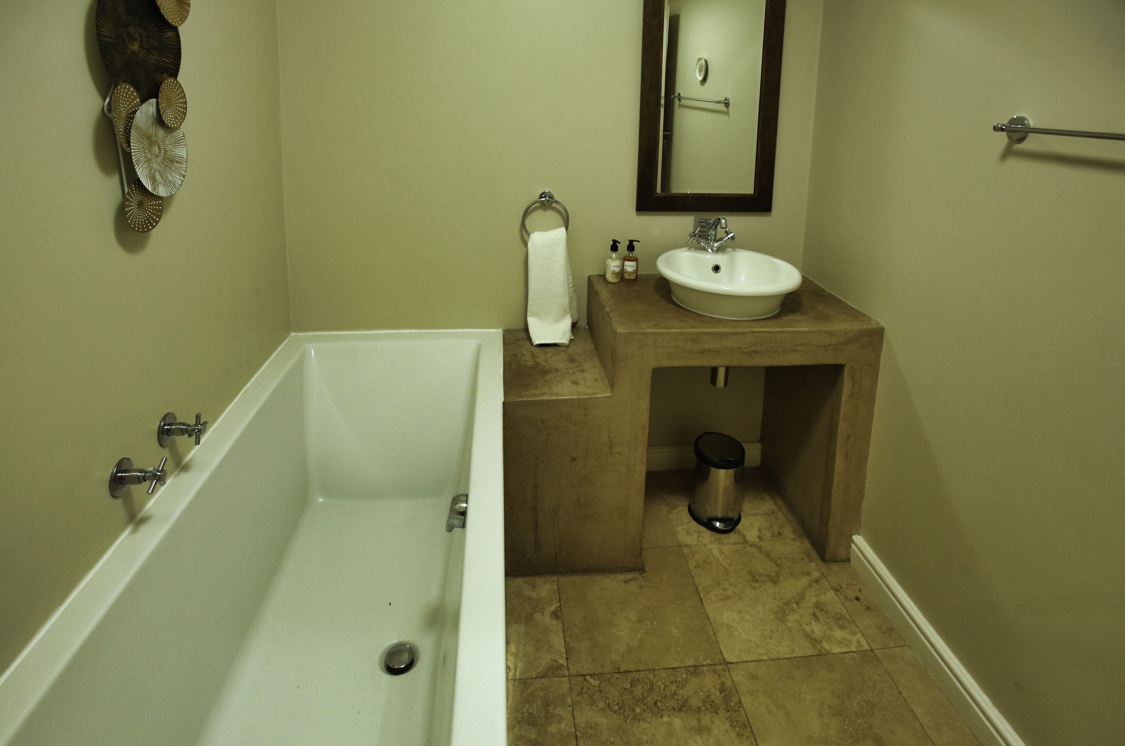 A bathroom with a bathtub, a sink, a mirror, and a towel rack.