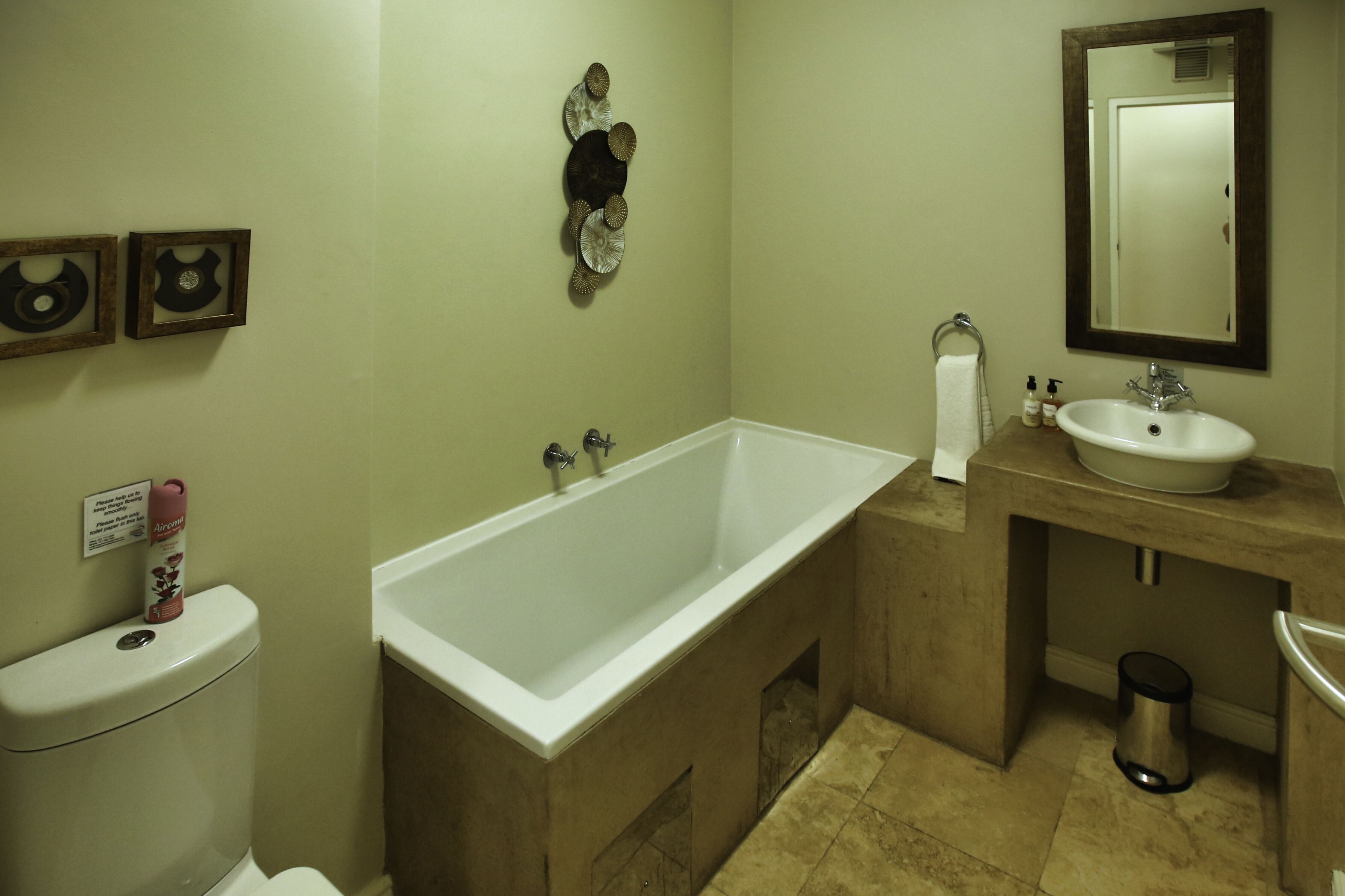 A bathroom with a bathtub, sink, and toilet. There are decorative wall pieces and a mirror above the sink.