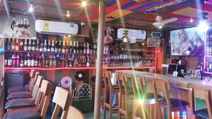 A bar with wooden chairs, a bar counter, and shelves of bottles.