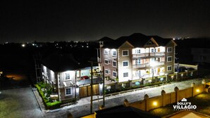 A multi-story building with balconies, a gated entrance, and a well-lit facade.