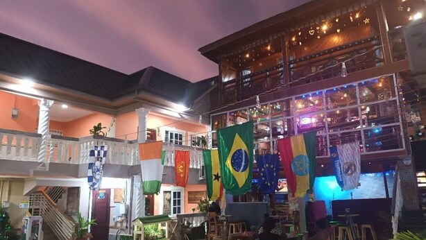 A multi-level building with outdoor seating areas, multiple flags, and a staircase.