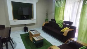 A living room with a TV, sofa, coffee table, and chairs.