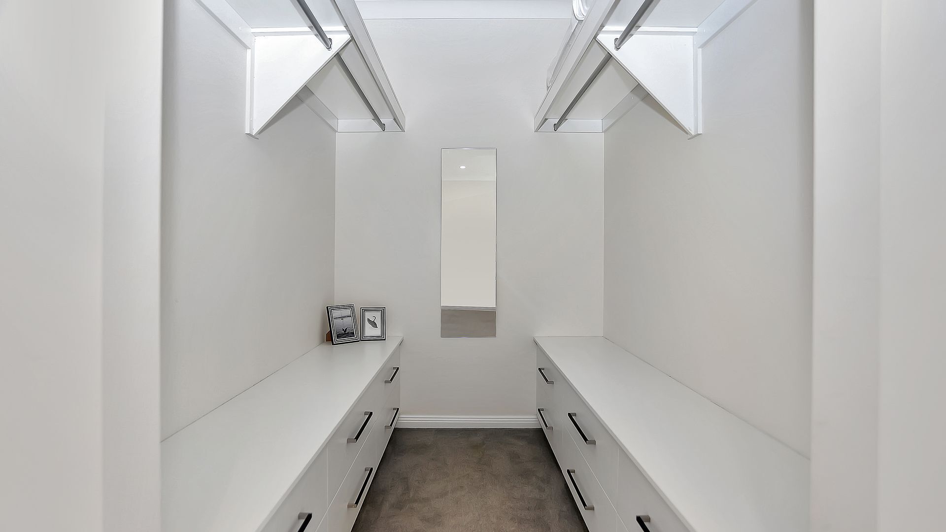 A narrow, white hallway with a central mirror and two side panels.