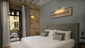 Un lit bien fait, avec des oreillers, une table de chevet surmontée d’une lampe et une œuvre d’art encadrée accrochée au mur.