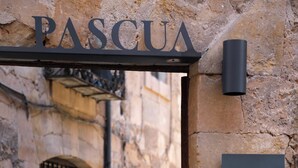 Un bâtiment en pierre avec une enseigne indiquant « PASCUA COCINA PURISTA » et une arche en métal.