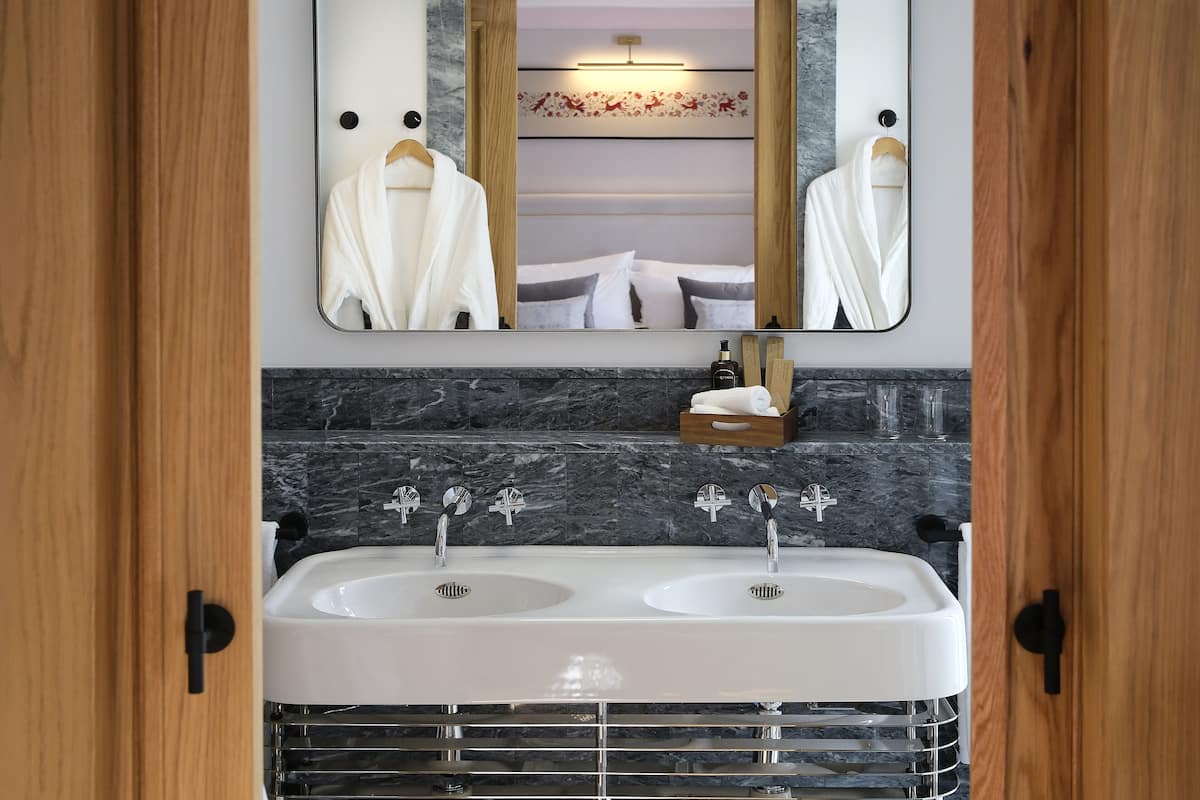 Een badkamer met een dubbele wastafel, een spiegel en een handdoekrek.