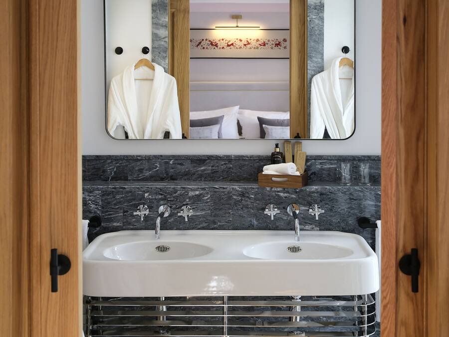 A bathroom with a double sink, a mirror, and a towel rack.