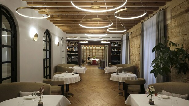 Un restaurant avec des planchers en bois, des tables blanches et un bar situé au fond de la salle.