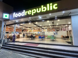 Un patio de comidas con un rótulo de 'foodrepublic', diferentes puestos de comida y zonas de estar.
