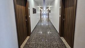 Un pasillo largo y estrecho con suelos de mármol pulido, puertas de madera e iluminación empotrada.