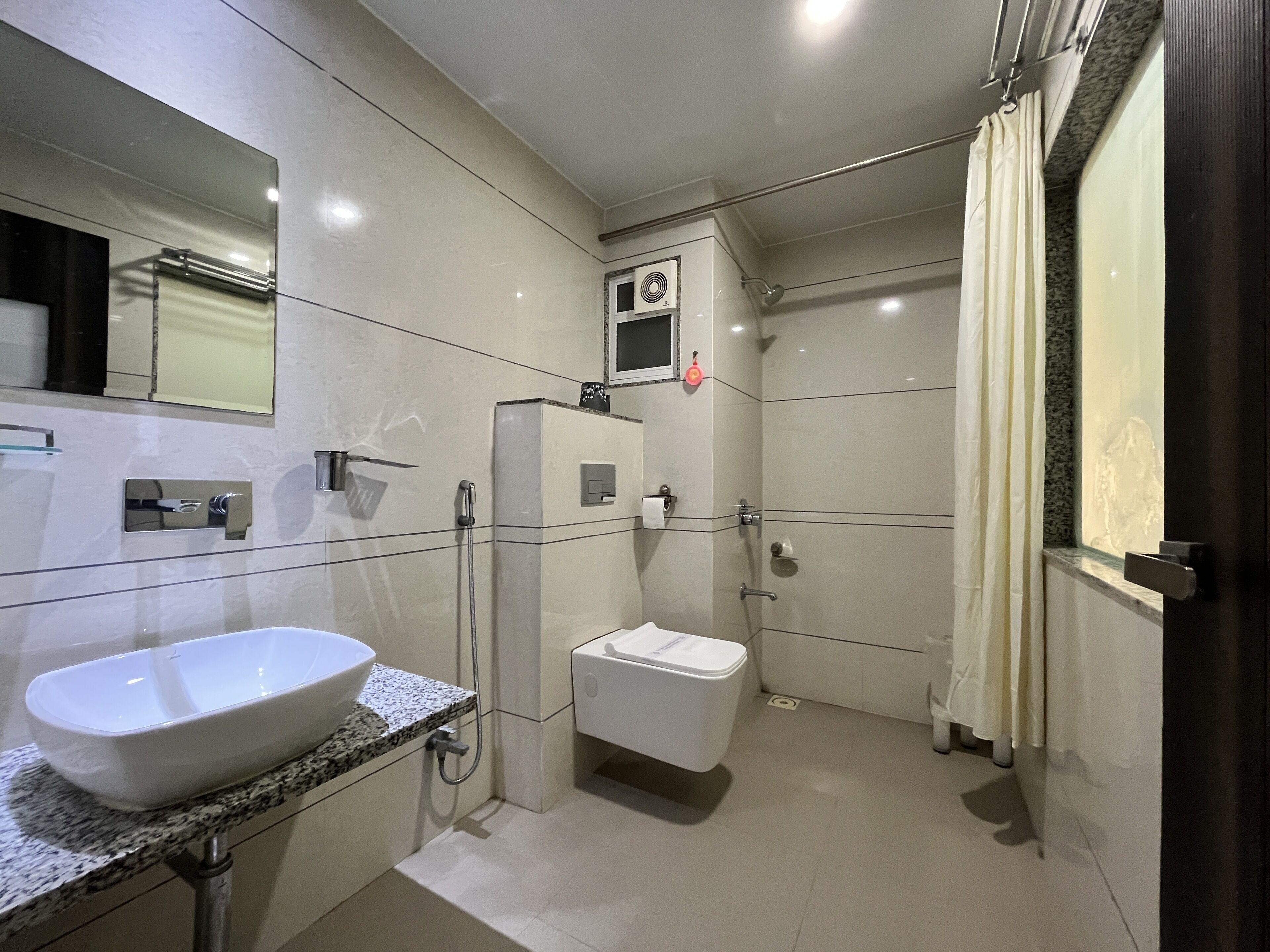 Un baño moderno con un lavamanos grande y blanco, un inodoro y una zona de ducha.