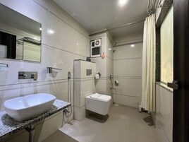 Un baño moderno con un lavamanos grande y blanco, un inodoro y una zona de ducha.