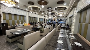 Un restaurante con cabinas y mesas, diseño moderno del techo e iluminación ambiental.