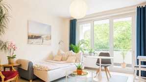 Ein modernes Schlafzimmer mit Bett, Nachttisch und Blick auf Grünfläche.