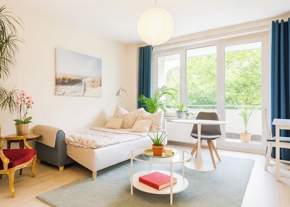 A modern bedroom with a bed, bedside table, and a view of greenery outside.