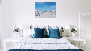 Ein Schlafzimmer mit einem Bett, zwei Nachttischen, einer weißen Lampe und einem gerahmten Bild an der Wand.