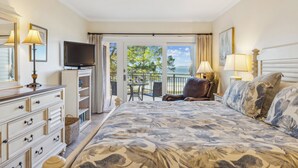 Une chambre à coucher comprenant un lit, une commode, une télévision et un balcon aménagé avec du mobilier d’extérieur.