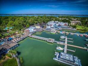 An aerial view of a marina with docked boats, a pier, and a building with a blue roof.