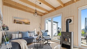 A cozy living room with a sofa, chairs, a table, and a fireplace. - Skippers Home - Terrace, Fireplace, Infrared Sauna, Free Pets Allowed (Olpenitz)