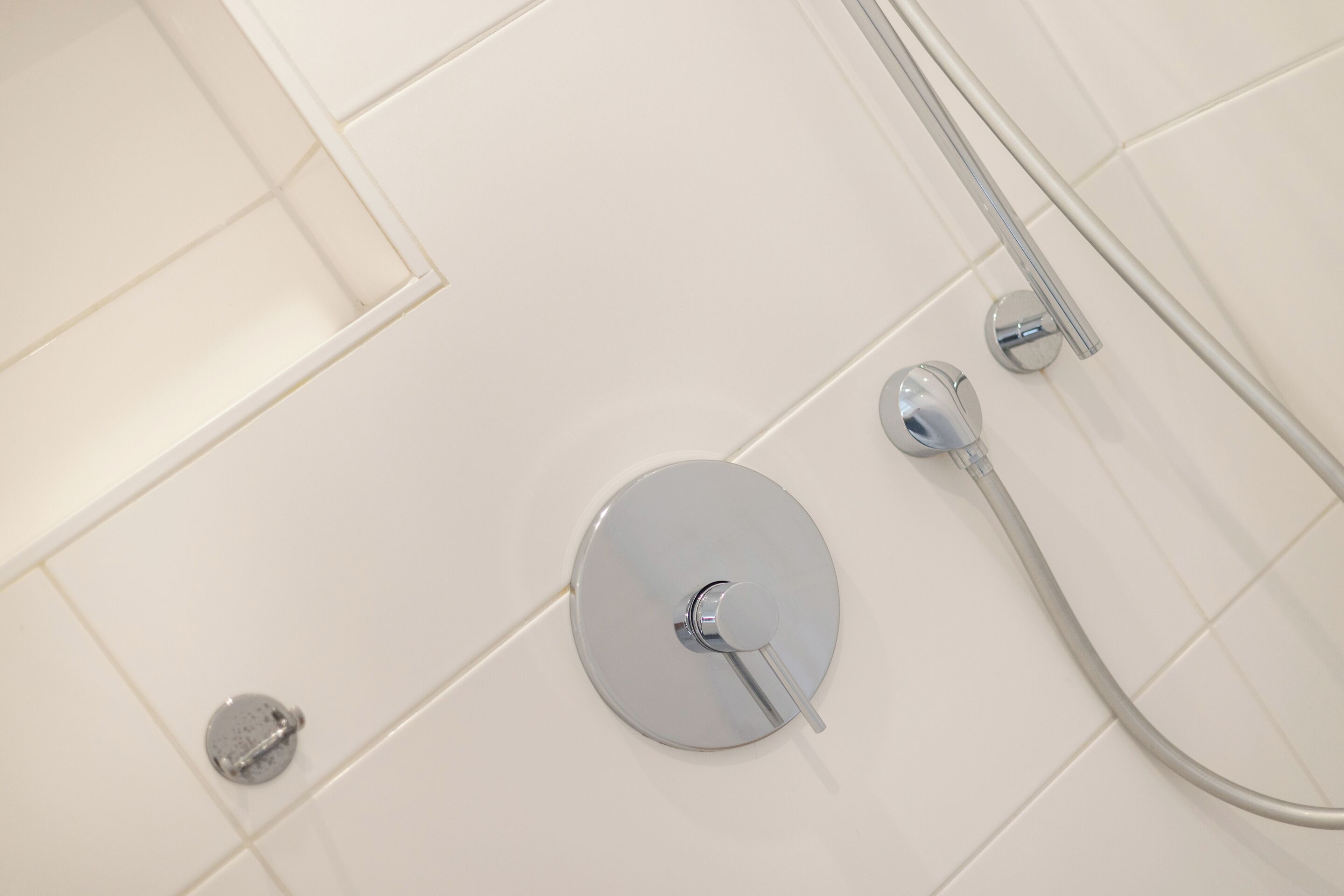 A shower with a handheld showerhead and a wall-mounted faucet.