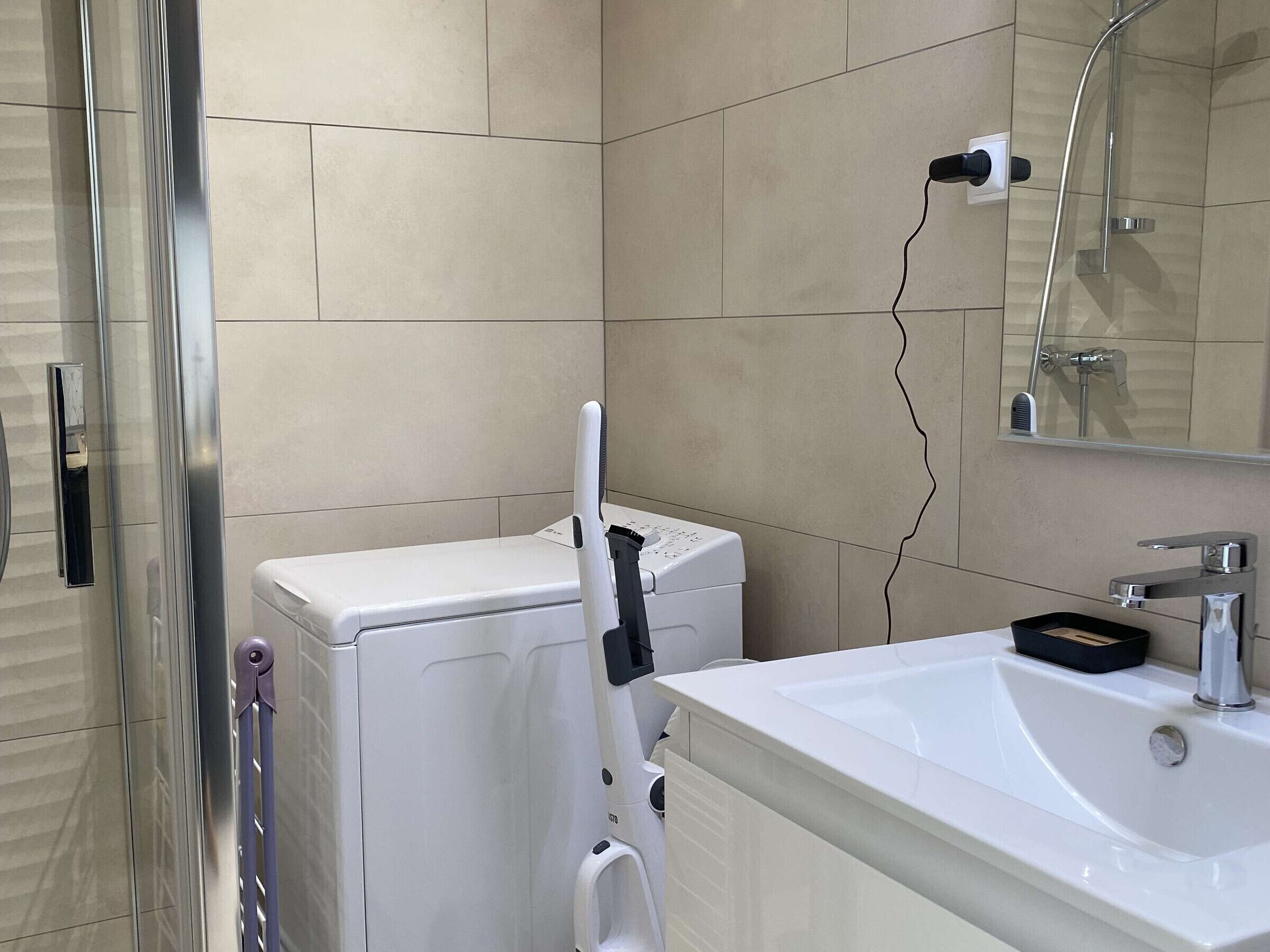 A bathroom with a white sink, a mirror, and a white washing machine.