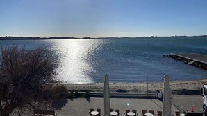A waterfront view with a dock, tables, and chairs for outdoor seating. - Air-conditioned studio with WIFI, Thau Lagoon view (Balaruc-les-Bains)