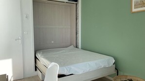 A compact room with a bed, a small table, and a wardrobe. - Air-conditioned studio with WIFI, Thau Lagoon view (Balaruc-les-Bains)