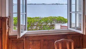 Ein Zimmer mit großem Fenster und Blick auf ein Gewässer und grüne Vegetation.