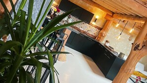 A modern kitchen with wooden beams, black cabinets, and a central island. - Charming Cottage with Jacuzzi in Forez Mountains (Saint-Jean-Soleymieux)