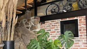 A room with a brick wall, a window, and a potted plant. - Charming Cottage with Jacuzzi in Forez Mountains (Saint-Jean-Soleymieux)
