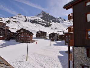 A snow-covered ski resort with multiple chalet-style buildings, a mountain in the background, and a clear sky. - Renovated apartment at slopes for 7 people (Belle Plagne)